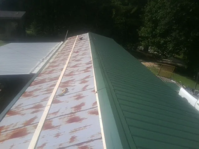 Old rusted panels beside newly installed green metal roofing — Wind Damage Roof Repair by Roofing Brothers in Gilmanton
