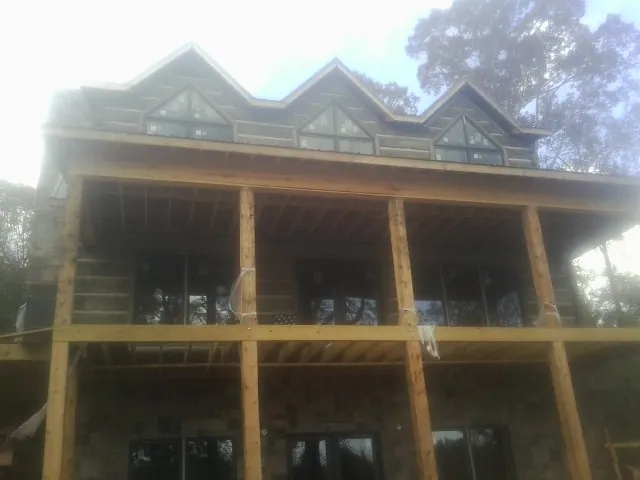 Dormers and porch framing on a large log home under construction — Roof Coating work by our crew in Gilmanton