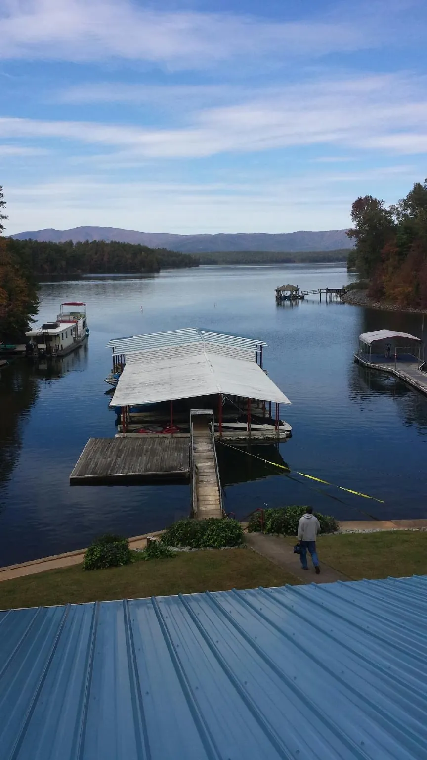 View across a lake from a newly installed blue metal roof in Gilmanton