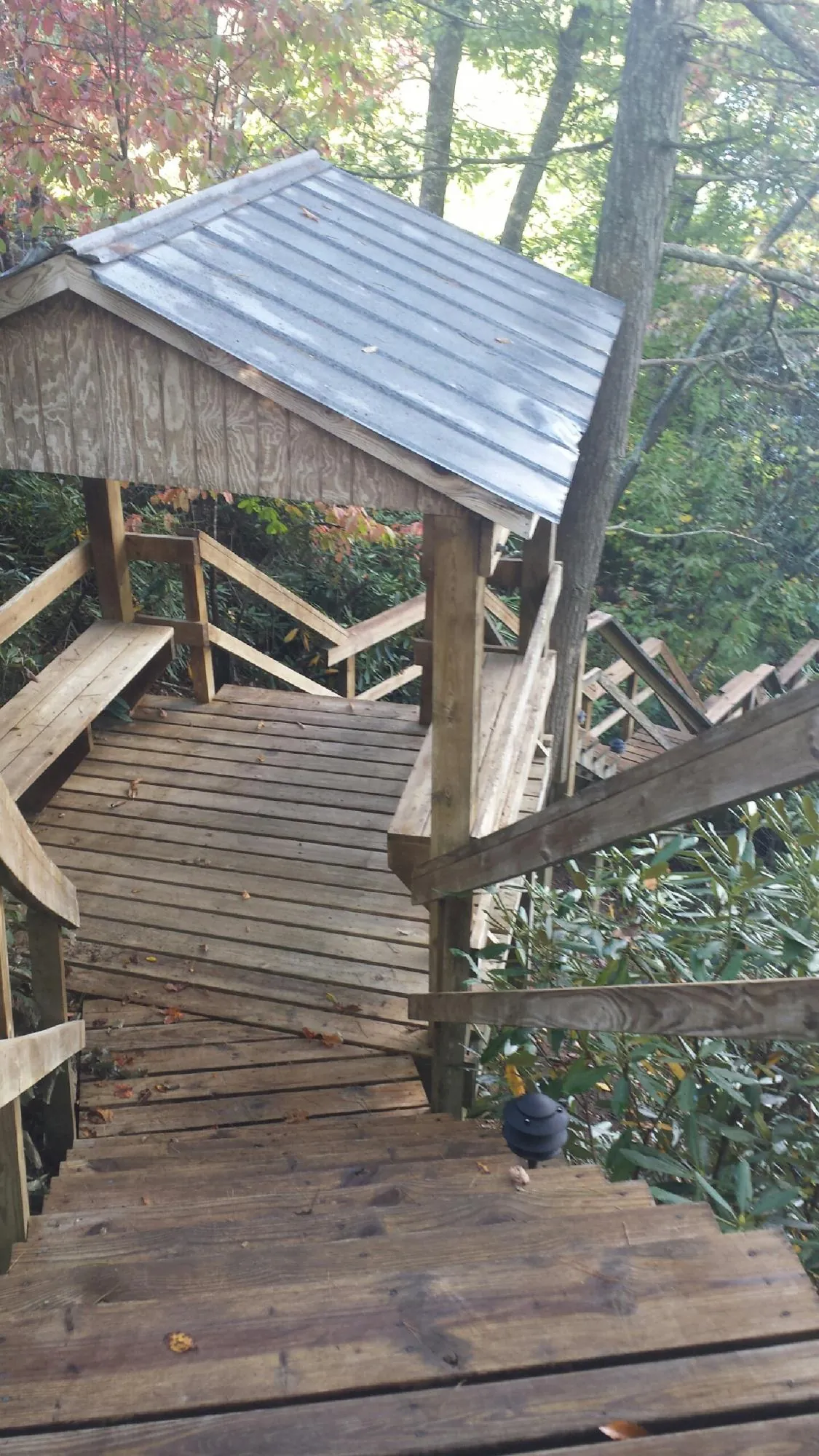 Metal roofed shelter over wooden steps on a wooded walkway — Skylight Repair & Installation work by our crew in Gilmanton