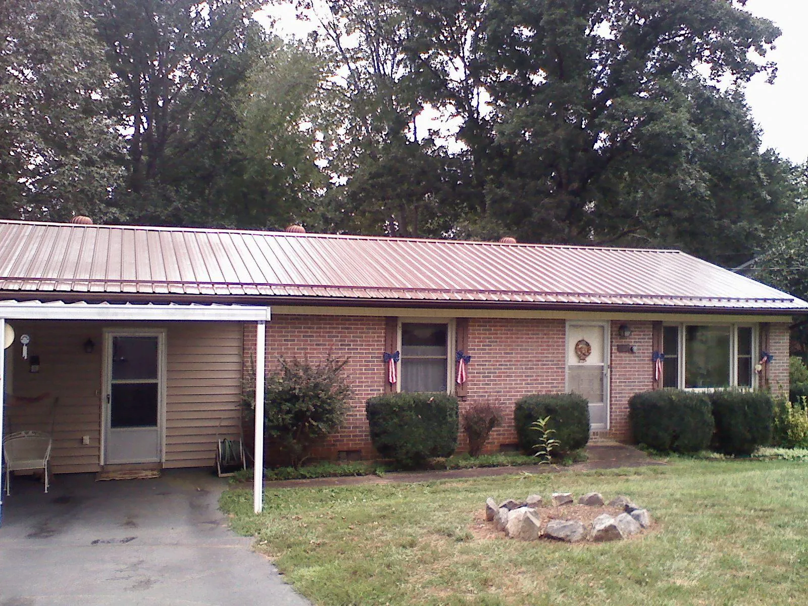 Bronze metal roof and carport on a brick ranch home — Roof Repair work by our crew in Gilmanton